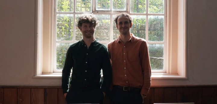 Two musicians stood by an old window