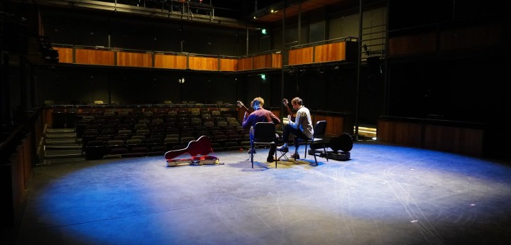 Two guitarists performing on a stage
